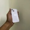 Rear view of a PTA approved Starlight White iPhone 13 mini held in hand showing the diagonal dual-camera layout and glossy glass back.