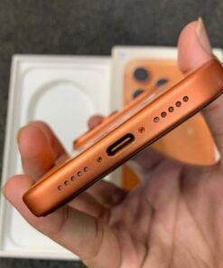 Bottom view of a copper orange iPhone 17 Pro showing the USB-C port and dual speaker grilles.