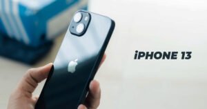 Hand holding a Midnight Blue Apple iPhone 13 showing the diagonal dual-camera layout and logo