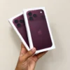 Front view of two concept iPhone retail boxes in deep burgundy purple held in hand against a neutral wall backdrop.