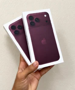 Front view of two concept iPhone retail boxes in deep burgundy purple held in hand against a neutral wall backdrop.